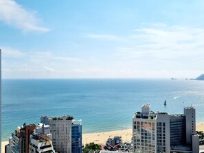 A coastal cityscape with a beach, a lighthouse, and several high-rise buildings including a hotel. - Haeundae Cotice Ambassador Hotel (Busan)