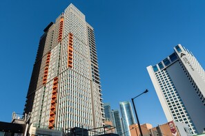 Een hoge, moderne wolkenkrabber met een rastergevel en oranje accenten.