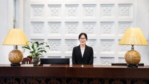 A reception desk with a patterned backdrop, two lamps, and a potted plant. - Hanoi Memory Premier Hotel Spa (Hanoi)