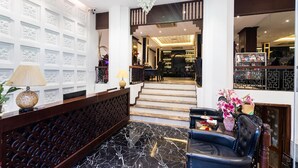 A lobby with a reception desk, a staircase leading to a bar area, and a seating area with a vase of flowers. - Hanoi Memory Premier Hotel Spa (Hanoi)
