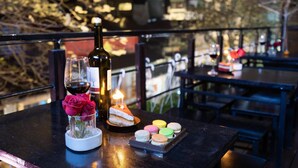 A table with a bottle of wine, a glass, a candle, a cake, and macarons. - Hanoi Memory Premier Hotel Spa (Hanoi)