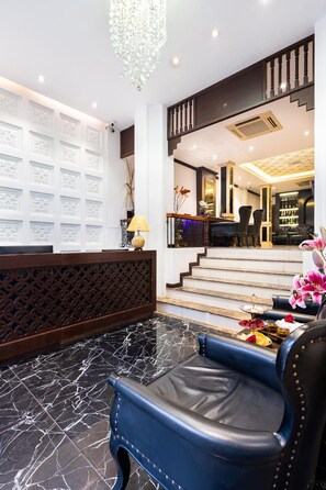 A lobby with a reception desk, a staircase, and a seating area with a blue chair. - Hanoi Memory Premier Hotel Spa (Hanoi)