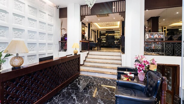 A lobby with a reception desk, a staircase leading to a bar area, and a seating area with a vase of flowers. - Hanoi Memory Premier Hotel Spa (Hanoi)
