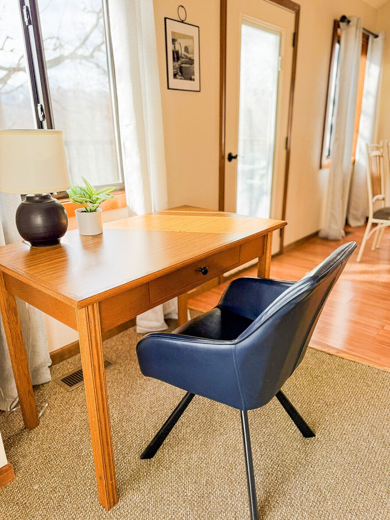 A wooden dining table with a blue chair, a potted plant, and a lamp.