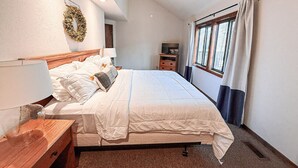 Een slaapkamer met een bed, nachtkastje, lamp en een raam met gordijnen.