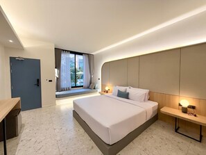 Une chambre d’hôtel moderne, dotée d’un grand lit, de tables de chevet, d’un bureau et offrant une vue sur l’extérieur.