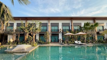Hotel com piscina, área de estar externa e edifício de vários andares com varandas.