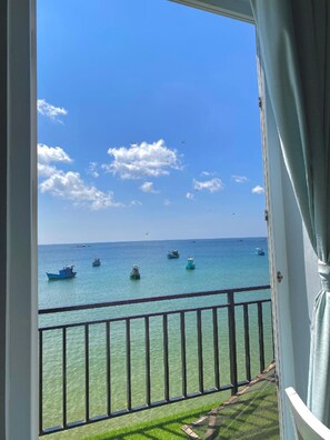 Un balcon offrant une vue dégagée sur la mer, avec plusieurs bateaux et une côte lointaine.