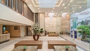 A spacious lobby with a high ceiling, a central floral arrangement, and seating areas. - B&n Hotel (Nha Trang)