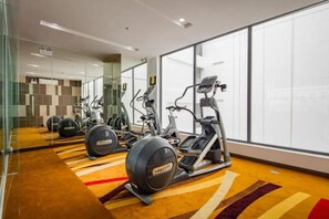 Une salle de sport moderne équip ée de machines de cardio, dotée d’un mur miroir et recouverte d’un tapis à motifs.