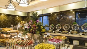A buffet with various food items, including fruits, pastries, and desserts, displayed on a marble countertop. - B&n Hotel (Nha Trang)
