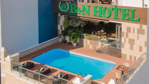 A rooftop pool area with lounge chairs and a sign for B&H Hotel. - B&n Hotel (Nha Trang)