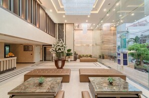 A spacious lobby with a high ceiling, a central floral arrangement, and seating areas. - B&n Hotel (Nha Trang)