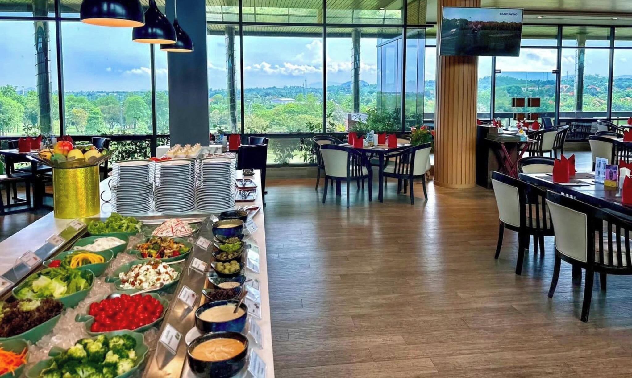 A buffet setup with various food items and a large window offering a scenic view.
