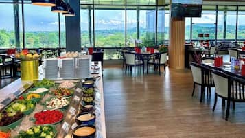 A buffet setup with various food items and a large window offering a scenic view.
