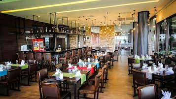 A restaurant with multiple dining tables, chairs, a bar area, and a view of the outside.