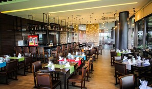 Un restaurante con varias mesas, sillas, una zona de bar y vistas al exterior.