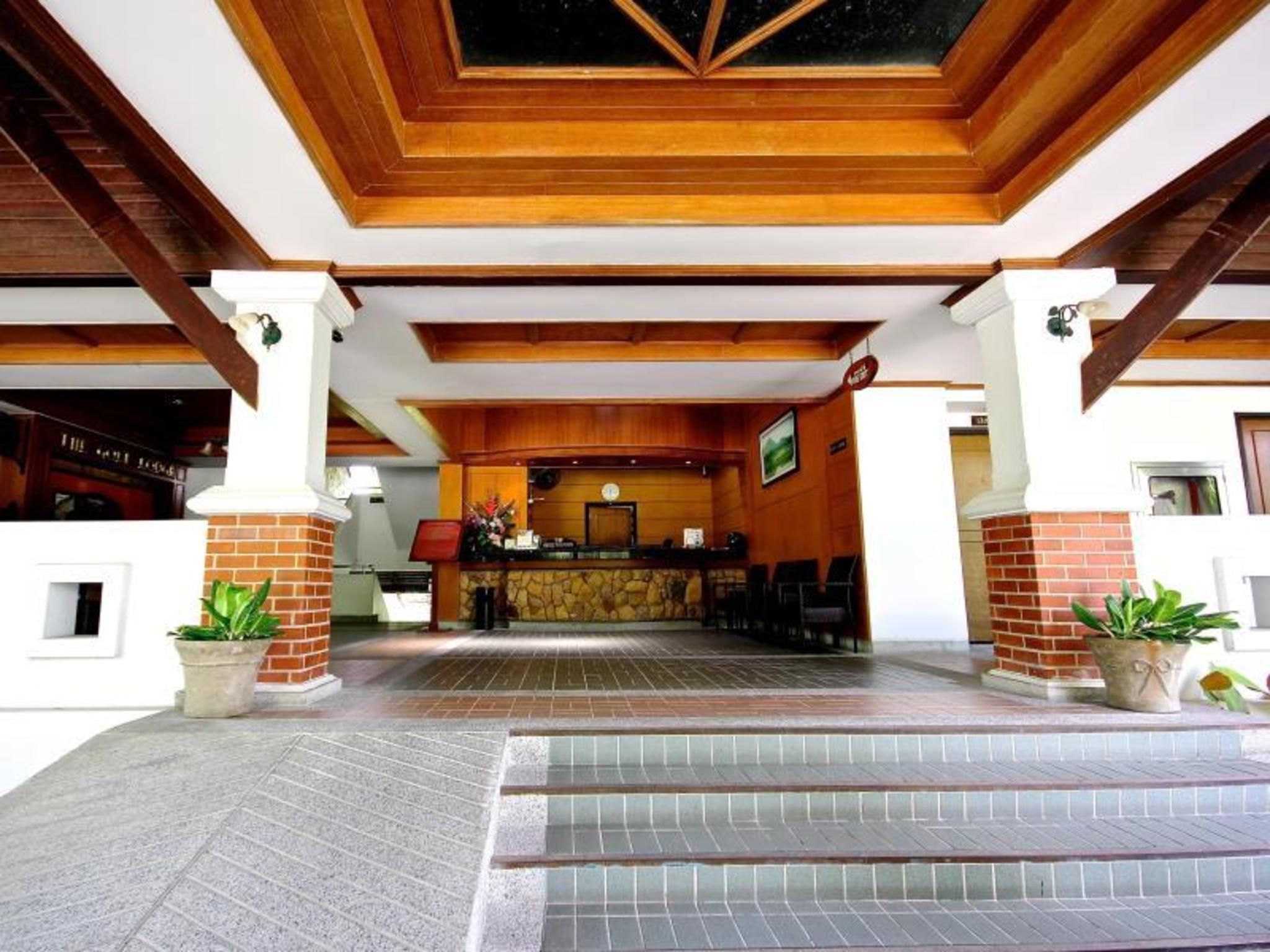 A reception area with a wooden ceiling, a reception desk, and potted plants.