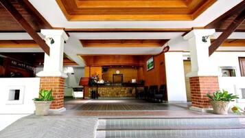 A reception area with a wooden ceiling, a reception desk, and potted plants.