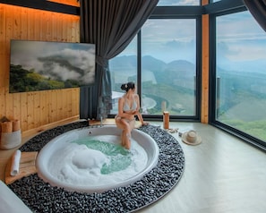 A spa room with a hot tub, a large window with a mountain view, and wooden walls. - Pino Latte Resort And Hotel (Khao Kho)