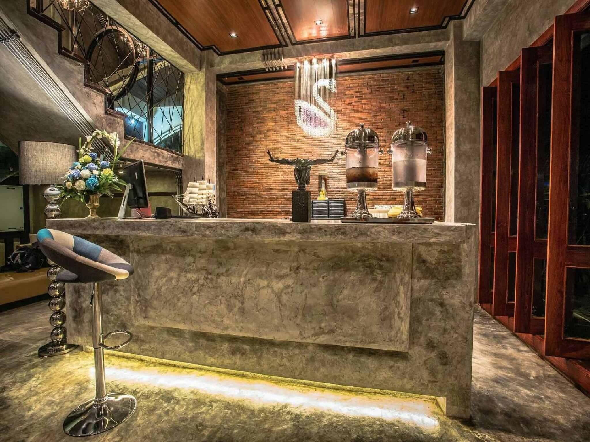 A reception area with a stone counter, a decorative s-shaped light fixture, and a modern chair.