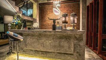 A reception area with a stone counter, a decorative s-shaped light fixture, and a modern chair.