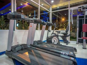 A gym with treadmills, an elliptical, and a weight machine. - Theloft Boutique Nakhonpanom (Nakhon Phanom)