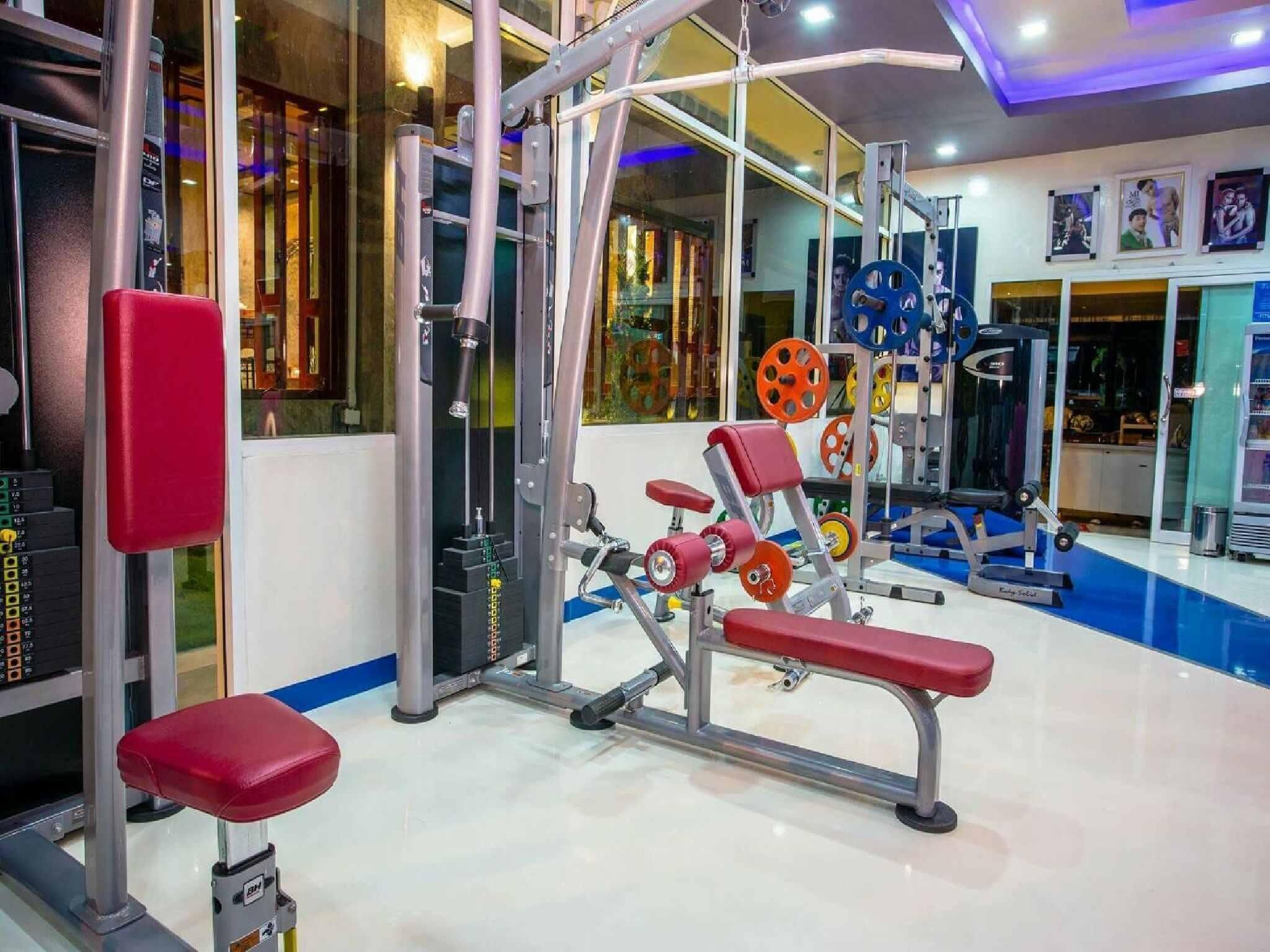 A gym with weightlifting equipment, benches, and a mirrored wall.