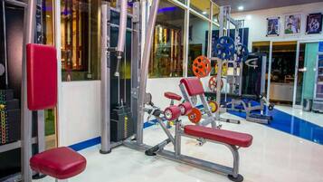 A gym with weightlifting equipment, benches, and a mirrored wall.