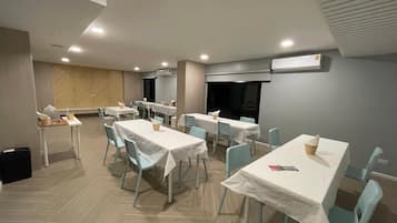 A dining area with multiple tables and chairs, air conditioning units, and a herringbone-patterned wall.