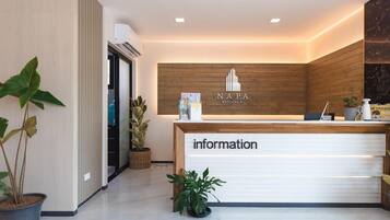 A reception desk with a wooden backdrop and the text "NAPA RATCHABURI" above it.