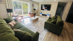 Una sala de estar con sofás verdes, una mesa de centro y un televisor.