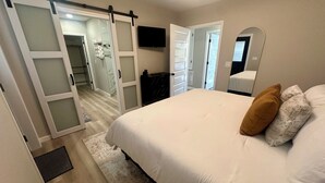 Un dormitorio con una cama grande, un armario corredero, un vestidor y un espejo en la pared.