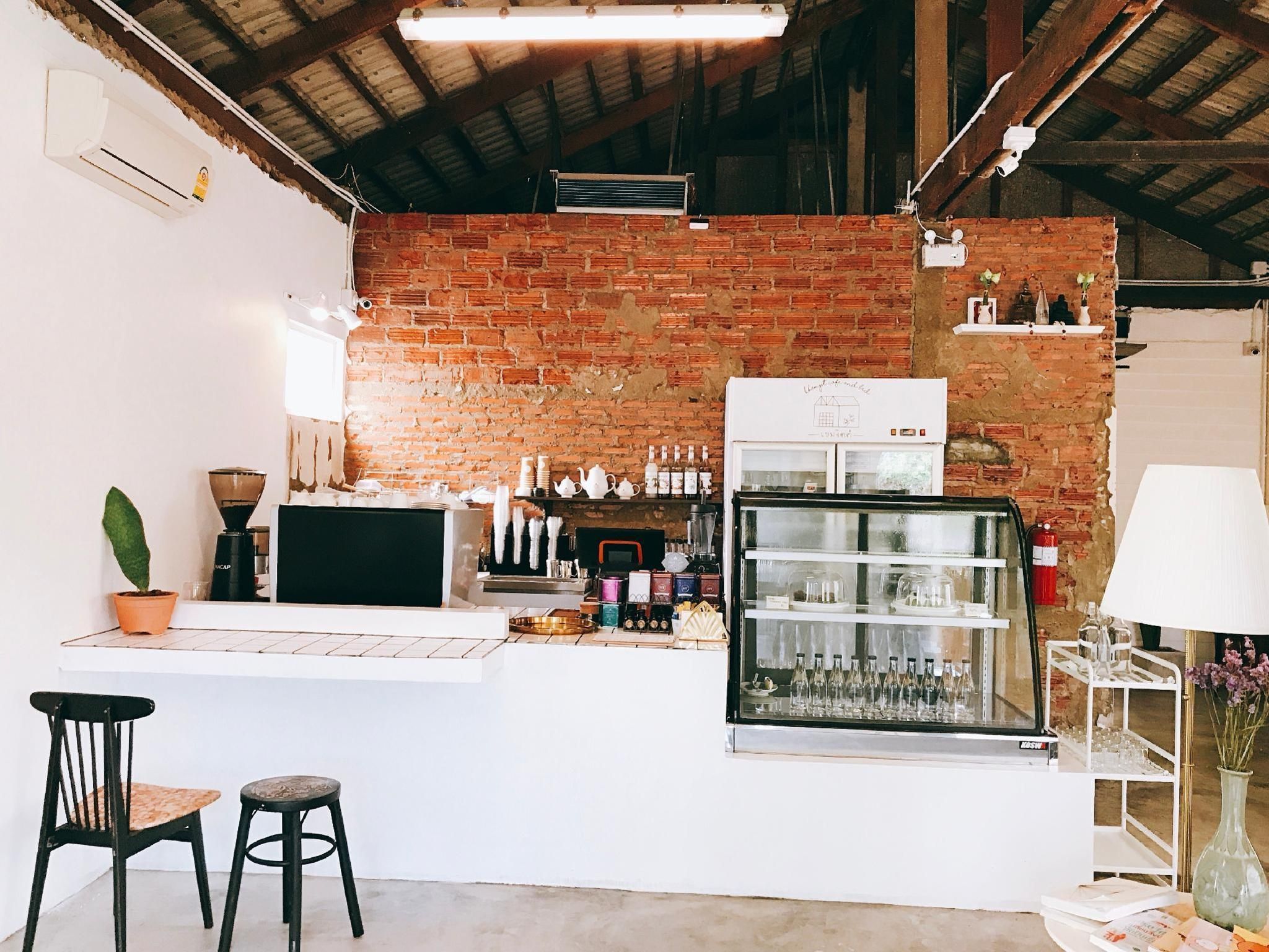 Una zona de bar con pared de ladrillo, un refrigerador y una barra con taburetes.