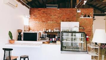 Una zona de bar con pared de ladrillo, un refrigerador y una barra con taburetes.