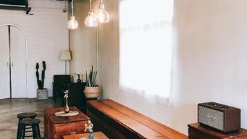 Un interior rústico con un banco de madera, taburetes, una radio antigua y lámparas colgantes.