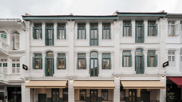 A white building with green shutters and a cafe on the ground floor. - Claude Hotel (Singapore)