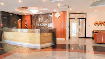 A reception area with a modern design, including a reception desk, a clock, and a chandelier.