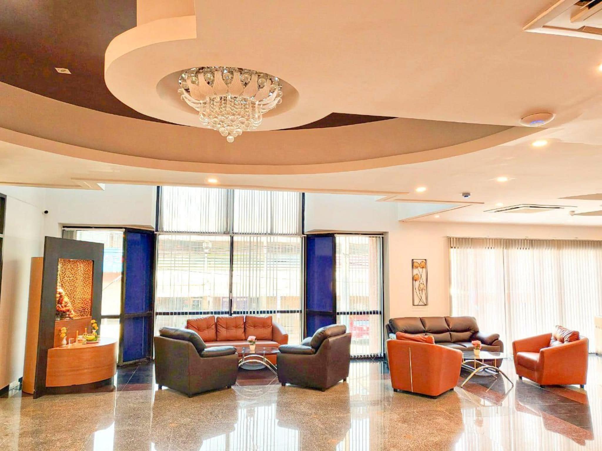 A modern lobby with a chandelier, leather sofas, and a polished floor.