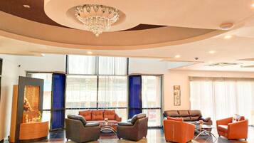 A modern lobby with a chandelier, leather sofas, and a polished floor.