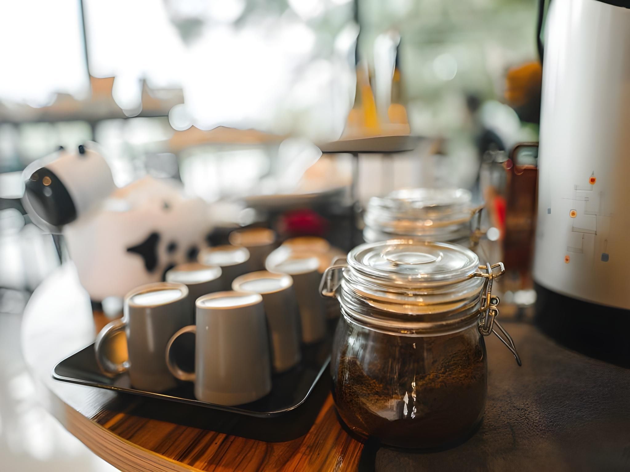 A tray with coffee mugs and a jar of coffee on a wooden table.