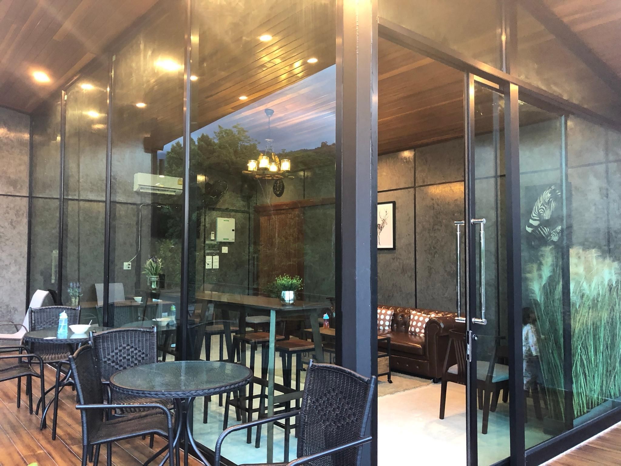 Un espacio interior moderno con paredes de vidrio, muebles de mimbre y techo de madera.