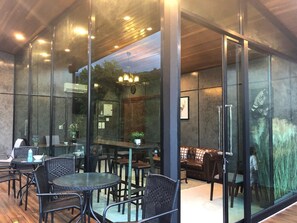 A modern indoor space with glass walls, wicker furniture, and a wooden ceiling. - The Sky Roof Homestay Kiriwong (Lan Saka)
