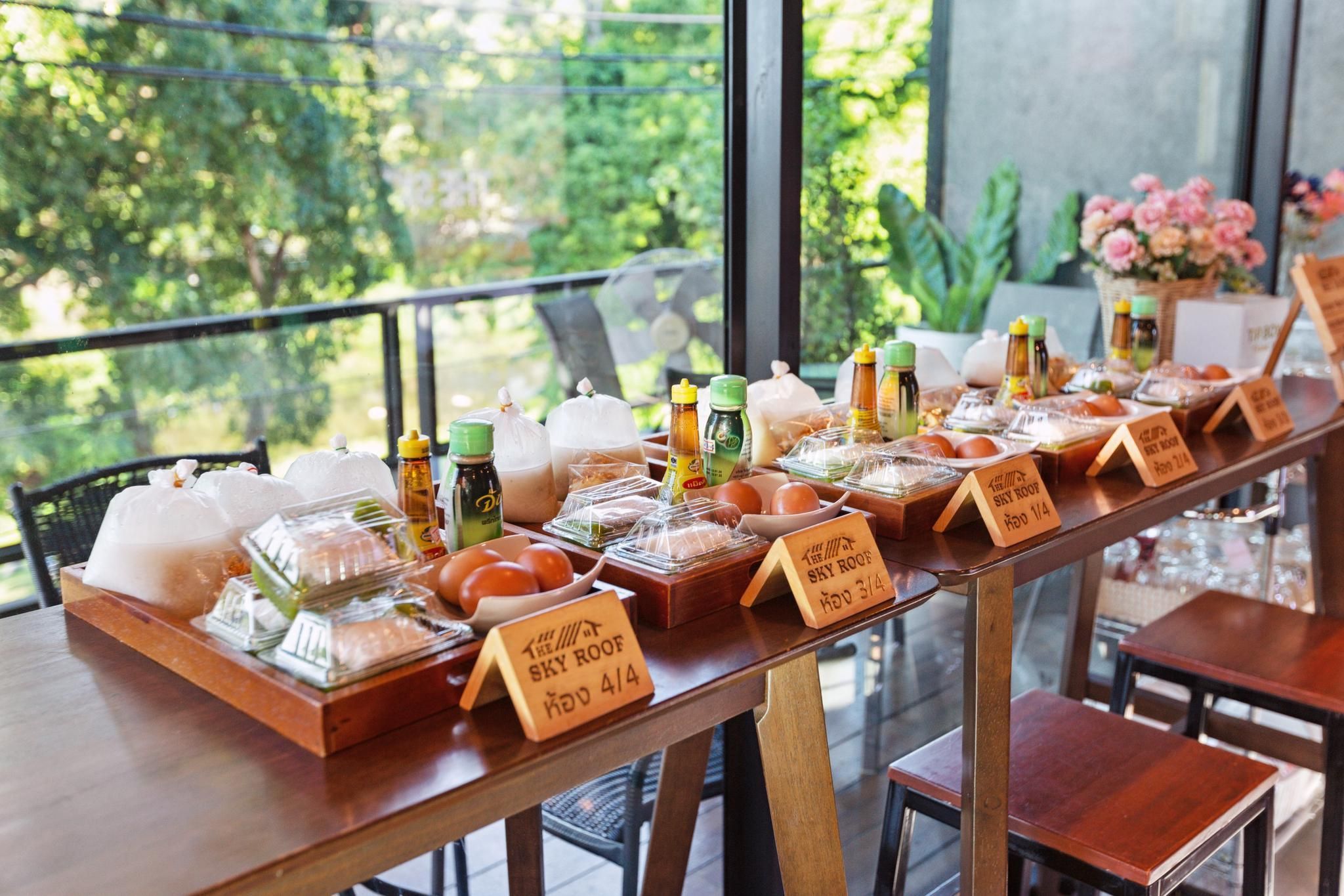 Una mesa de buffet con diversos alimentos y aderezos, con precios indicados en un restaurante.
