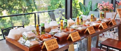 Una mesa de buffet con diversos alimentos y aderezos, con precios indicados en un restaurante.
