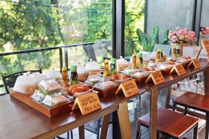 A buffet table with various food items and condiments, labeled with prices in a restaurant setting. - The Sky Roof Homestay Kiriwong (Lan Saka)
