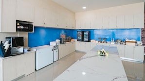 Une cuisine moderne avec des meubles en bois clair, un mur d’accent bleu et un sol en marbre.