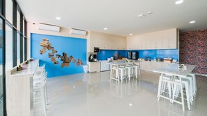 Une cuisine moderne avec un mur d’accent bleu, des meubles blancs et un îlot central doté de tabourets de bar.