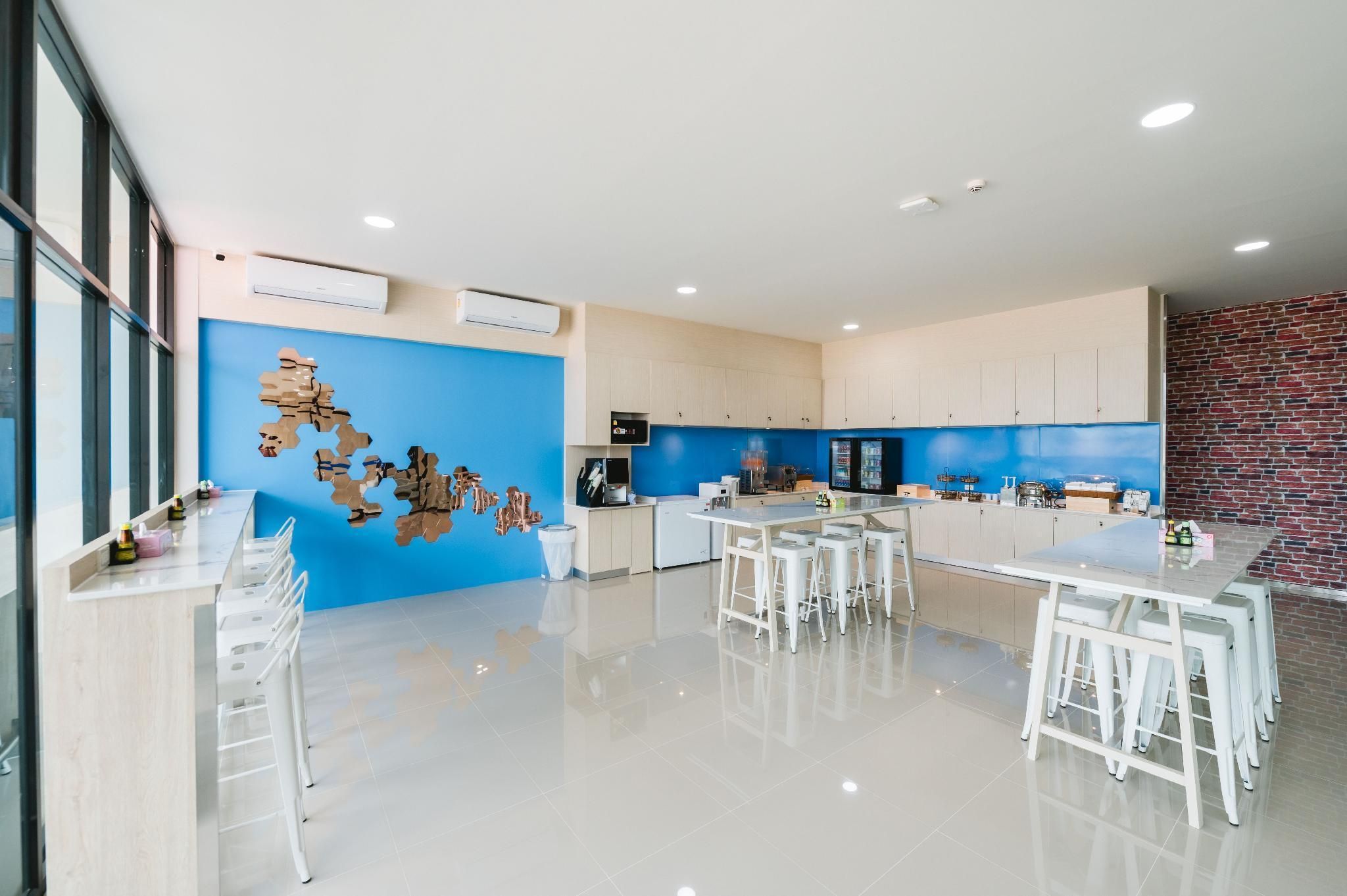 A modern kitchen with a blue accent wall, white cabinetry, and a central island with bar stools.