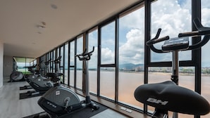 Une salle de sport équipée de matériel d’exercice et dotée de grandes fenêtres donnant sur une rivière.